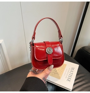 Detail of red patent leather mini crossbody bag with silver C-buckle and metal chain strap