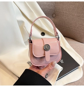 Detail of pink patent leather mini crossbody bag with silver C-shaped buckle and chain