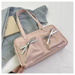 Detail of light pink patent leather tote bag with silver bows and front pockets