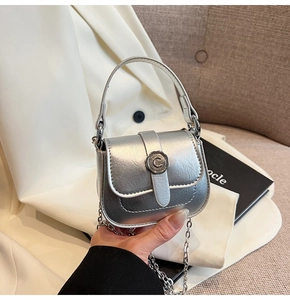 Macro view of silver metallic mini bag with 'C' buckle and chain strap detail