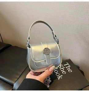 Detail of a silver metallic mini crossbody bag with a C-shaped buckle and chain strap