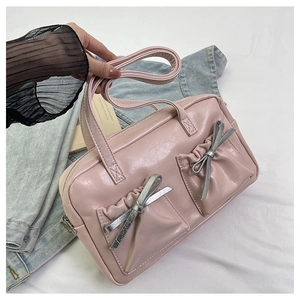 Detail of light pink patent leather tote bag with silver bow and front double pockets