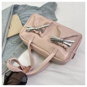 Detail of pink PU leather tote featuring decorative silver bows and gathered textures