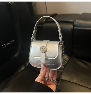 Detail of silver mini crossbody bag featuring a metal C-shaped buckle and chain strap