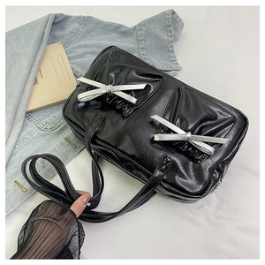 Detail of black pleated faux leather tote bag with silver bow charms and zipper
