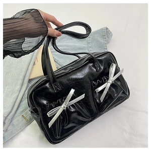 Close-up of black glossy patent leather tote bag with silver glitter bow details