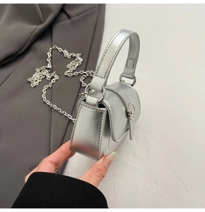Detail of silver mini chain bag showing metallic leather texture and round metal buckle
