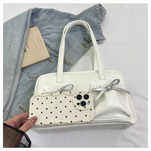 Close-up of cream bow tote bag next to polka dot phone case on blue denim background