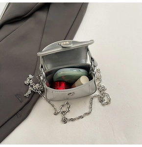 Detail view of mini silver metallic bag interior with chain strap and cosmetics storage