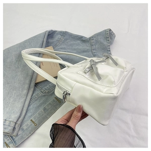 Detailed close-up of white PU leather tote with silver zipper and grey bow decoration