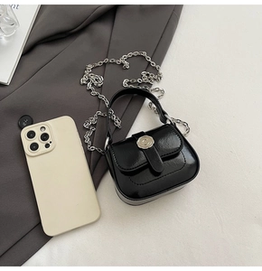 Detail of a mini black glossy square bag with silver C buckle and metal chain strap