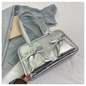 Detail of silver metallic tote bag featuring bow pockets and glossy leather texture