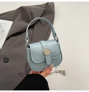 Detail of light blue mini bag featuring a silver flower clasp and delicate chain strap