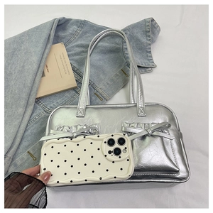 Silver metallic tote bag with bow details shown next to phone case for size reference