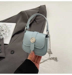 Detail of baby blue mini saddle bag with silver C-buckle and metal chain strap