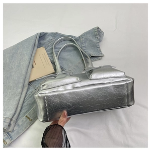 Detail of silver metallic tote bag featuring pleated texture and bow decoration