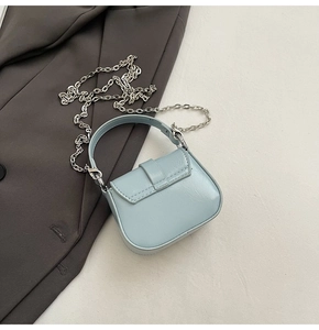 Detail of light blue mini PU leather crossbody bag with silver chain and top handle