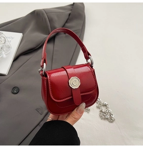 Detail of red patent leather mini handbag with silver chain and metal C buckle