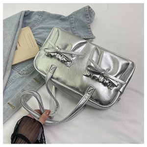Detail of silver tote bag featuring pleated texture and elegant bow decorations