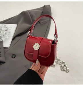 Detail of red mini leather saddle bag with silver petal buckle and chain strap