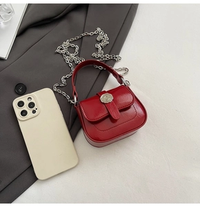 Detailed close-up of a mini red square chain bag with silver buckle and phone for scale