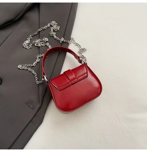 Close-up of a mini red glossy patent leather handbag with a silver metal chain strap
