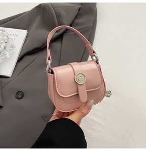 Macro view of a pink mini crossbody bag featuring a metal floral buckle with C-embossing