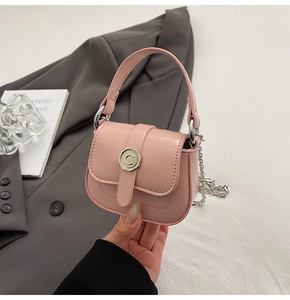 Detail of pink mini bag featuring lychee leather texture and silver C-buckle with chain