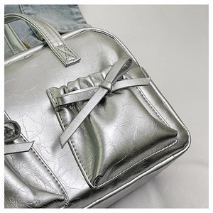 Macro view of silver metallic tote bag featuring pleated pockets and stylish bow details