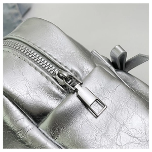 Close-up of metallic silver tote bag featuring pleated texture and premium metal zipper detail