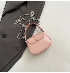 Close-up of pink patent leather mini bag with silver chain on a grey blazer suit