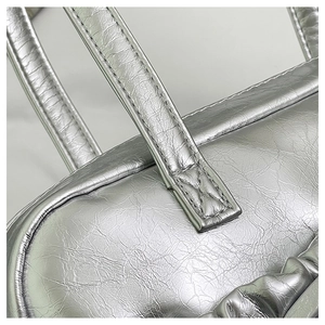 Macro detail of fine stitching on silver metallic bow tote bag with pleated texture