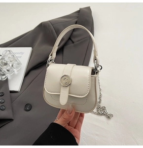 Detail view of cream mini square bag featuring silver C-buckle and metal chain strap
