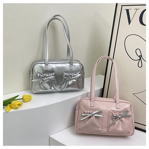 Detail of silver and pink bow-knot tote bags on a minimalist platform with tulips