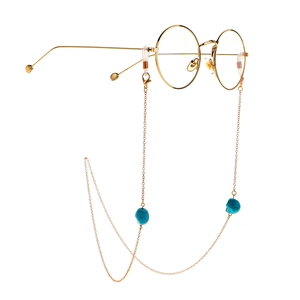 Golden round frame glasses featuring a turquoise skull charm chain on white background