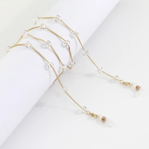 Detail of gold glasses chain with clear crystal squares on a white display stand