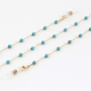 Golden eyewear chain with turquoise beads and adjustable rubber loops on white backdrop