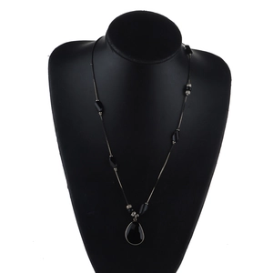 Detailed view of long sweater necklace with black water drop pendant and snake chain beads