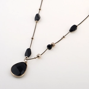 Elegant gold sweater chain featuring a black faceted teardrop pendant and beaded snake link