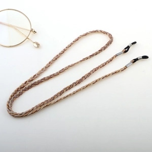 Detail of woven brown eyewear lanyard with non-slip rubber loops and silver hardware