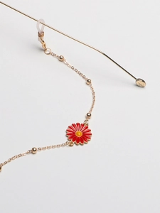 Close-up of golden metal eyewear chain with red daisy pendant and anti-slip silicone loops