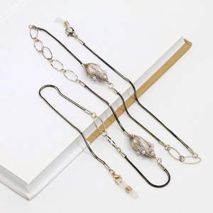 Chaîne à lunettes dorée élégante avec perles et chaîne serpent sur un livre