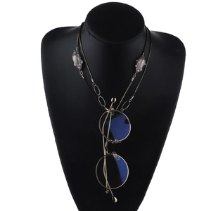 Détail d'une chaîne serpent dorée avec perles sur un buste noir pour lunettes