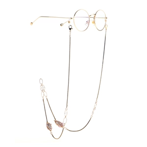 Chaîne à lunettes dorée avec perles et breloques feuilles sur fond blanc pur