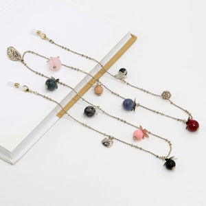 Golden eyewear chain with leaf charms and colorful semi-precious beads on white background