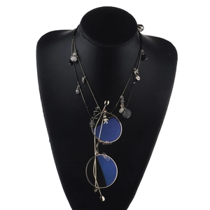 Détail du pendentif lunettes dorées sur une longue chaîne à perles sur buste noir