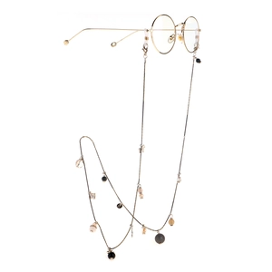 Chaîne de lunettes dorée multi-éléments avec perles noires et cristaux sur fond blanc