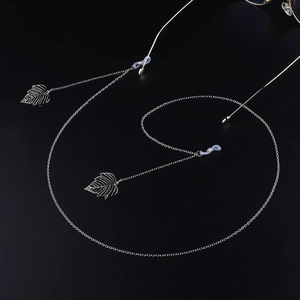 Silberne Brillenkette aus Metall mit hohlen Blattanhängern auf schwarzem Hintergrund