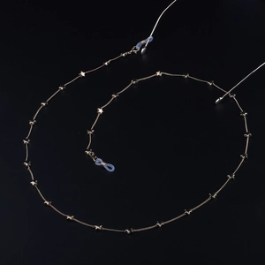 Catenina per occhiali dorata con stelle e asole in silicone su sfondo nero opaco