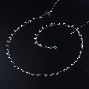 Fashion gold metal eyeglass chain with white faux pearls on a black background